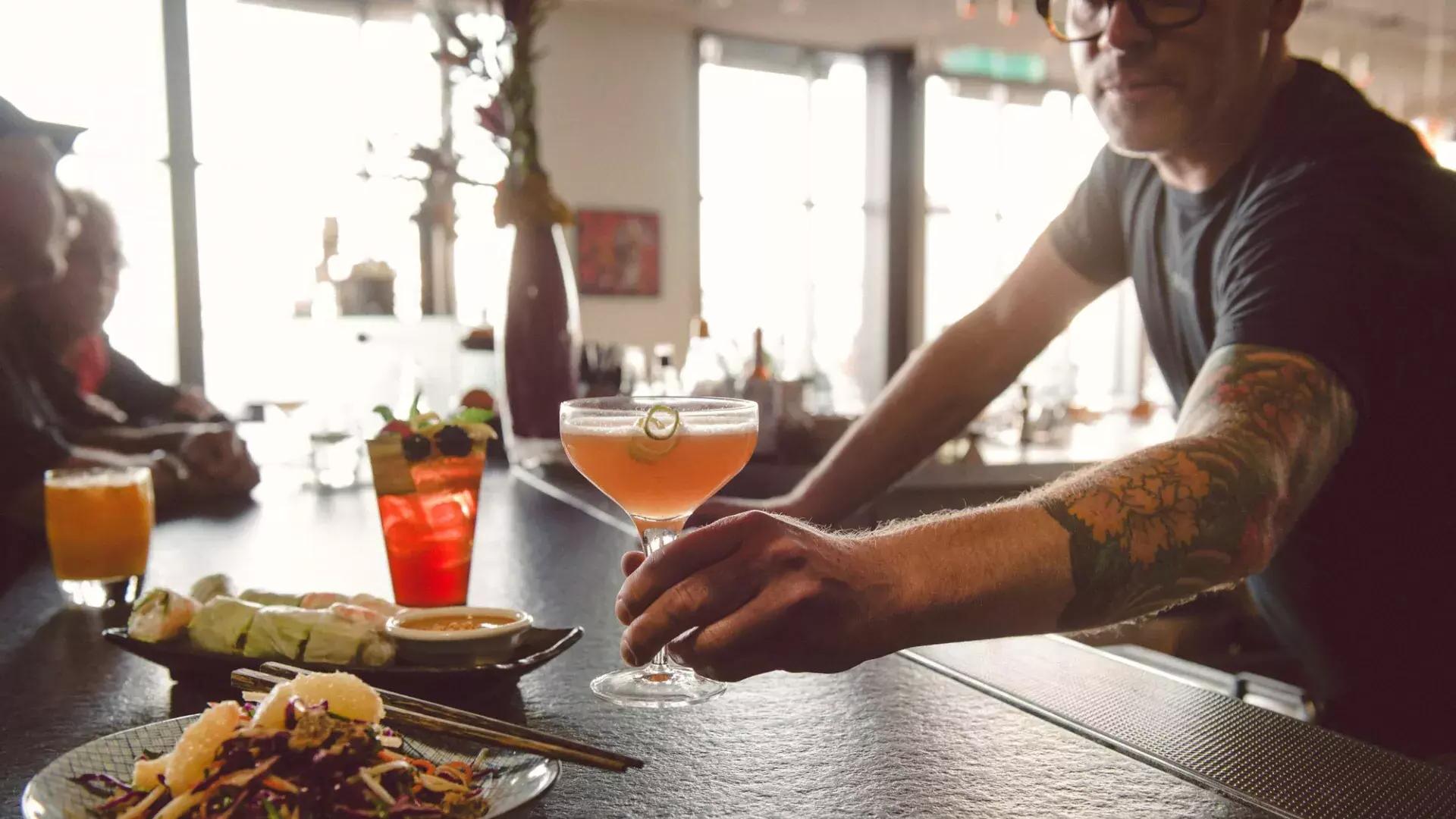 在贝博体彩app的一家酒吧里，酒保为顾客端上鸡尾酒.