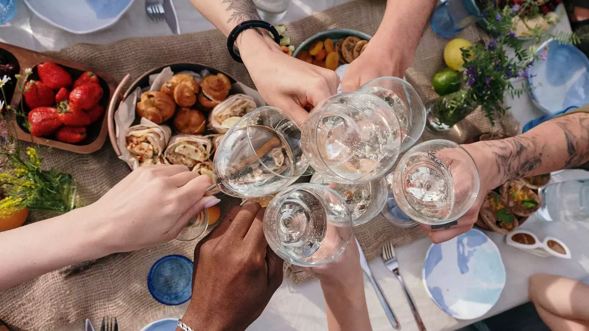 Overhead shot of a group of people clinking glasses at a brunch table.