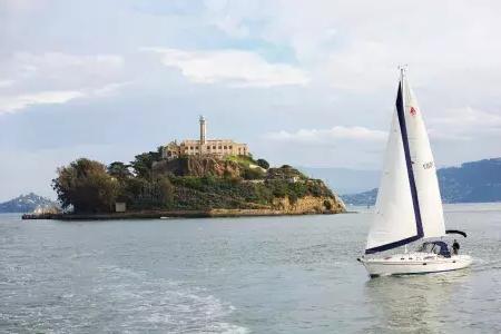 A sailboat passes in front of Alcatraz Island in San Francisco.